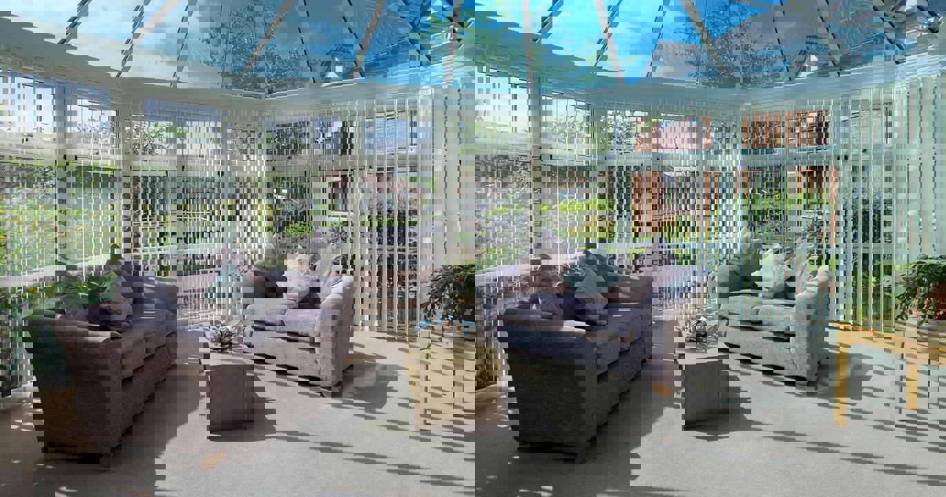 A conservatory-type room, with two sofas and a coffee table inside